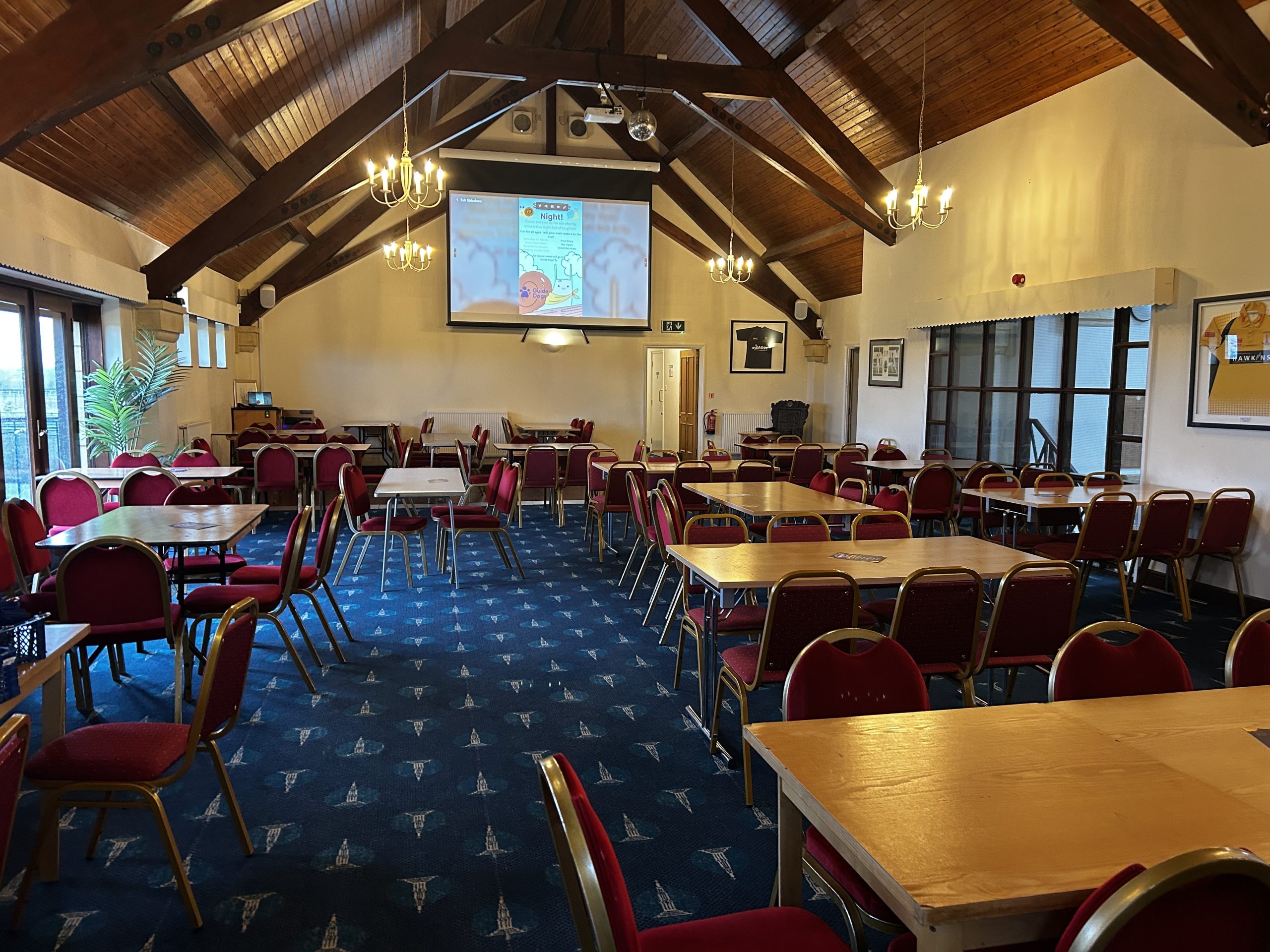 A dining room set up for a conference with tables and a projector set up